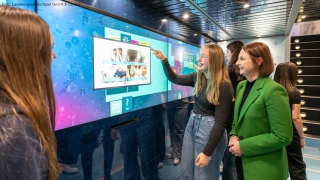 Staatssekretärin Sandra Boser mit einer Schülerin, die auf einen Bildschirm zeigt. Foto: Landesmesse Stuttgart GmbH & Co. KG