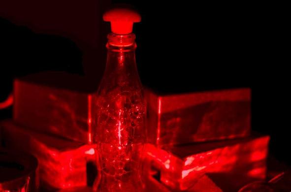 A glass bottle, filled with bubbles, immersed in red light