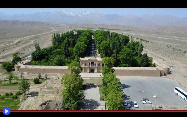 Veduta aerea del complesso di un giardino formale circondato da una cinta muraria, con viali alberati nonostante si trovi nel mezzo di un arido deserto. L'architettura del portone d'ingresso mostra caratteristiche mediorientali.