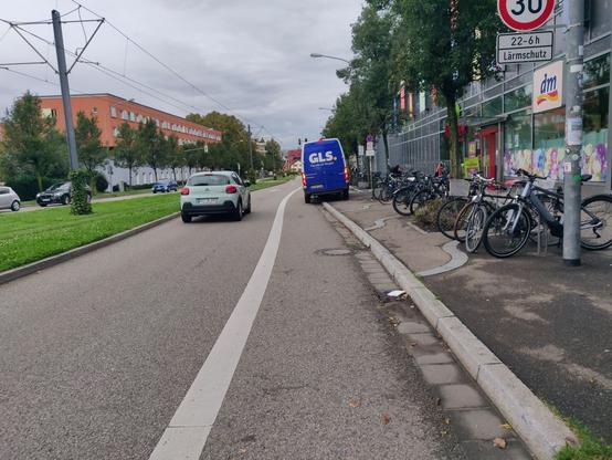 Ein GLS-Lieferfahrzeug ist halb auf dem Gehweg, halb auf dem auf der Fahrbahn durch eine breite Linie separierten Fahrradweg abgestellt.