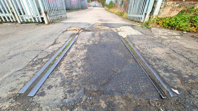 A short section of old railway line embedded in the pavement of a modern street.