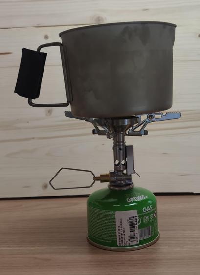 A MSR 900ml Titanium kettle (previous generation) atop of a small XD-2F stove whic in turn, is atop of a small Optimus gas canister.