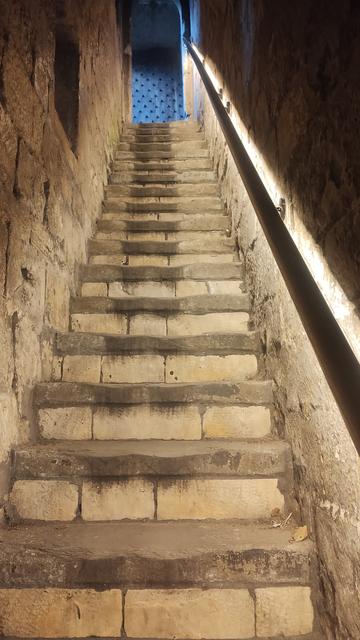 Looking up a narrow, steep flight if stone steps in a medieval gatehouse leading to York city walls
