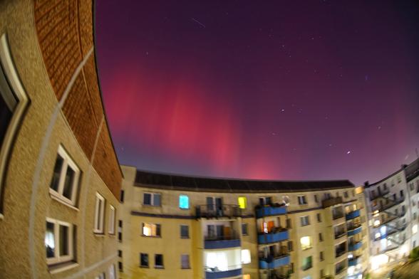 Rötliche Polarlichter über einem Häuserblock