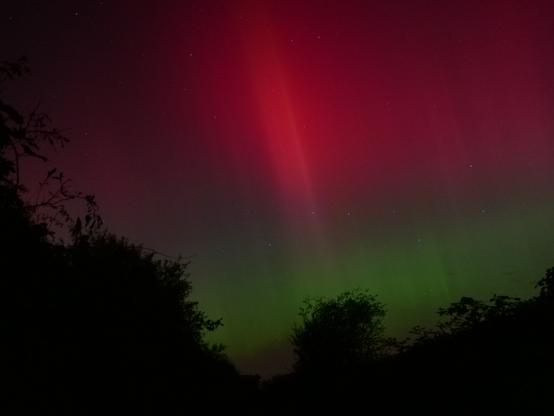 Auf diesem Foto ist die Aurora ein hell leuchtender Oval mittig im Bild