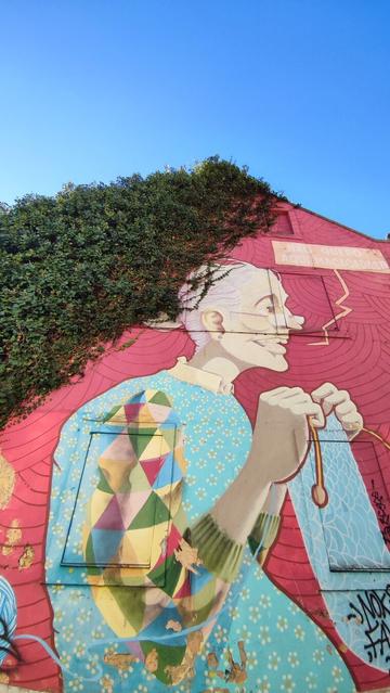graffiti de persona tejedora con vegetacion en la parte de arriba