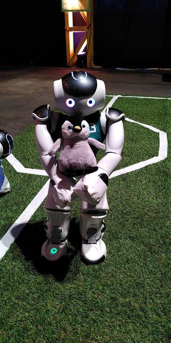 The same robot as in the previous photo is now  holding Archy in his arms.