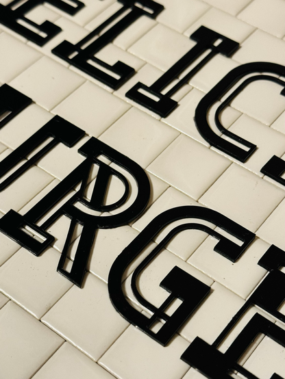 A closeup photo of black letters on a white tile background.