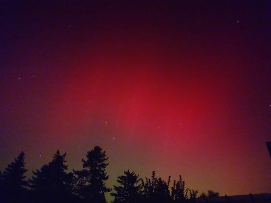 The same view with s tree line, this time work an intensely red glow across the horizon reaching up into the sky. Some stars are visible.