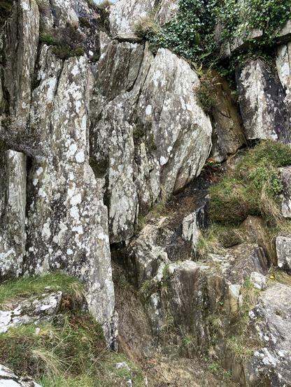 Picture of a scramble, where the trail goes abruptly vertical to get past a rock. The foot / hand holds can be seen where the rock is worn.   Not one for the novices!