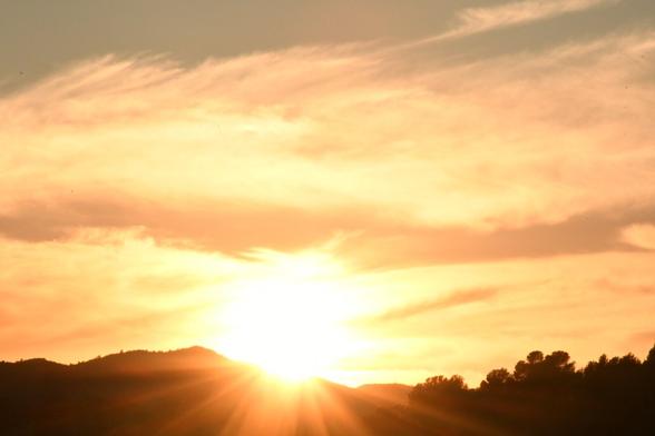 El sol al atardecer. Algunos de sus rayos atraviesan cubren unas montañas