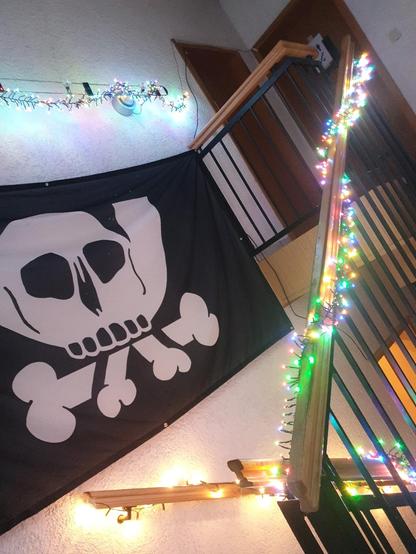 Zu sehen ist ein Treppenraum mit Lichterketten an der Wand und Geländer sowie einer Chaosflagge mit Pesthörnchen an der Wand