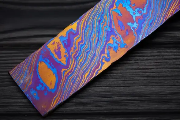 three layers of damascus titanium heat treated to make orange, blue and purple layers based off oxidization.

This one has a wood veneer like lined pattern and only some wider areas of orange and purple in between