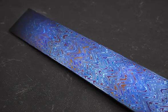three layers of damascus titanium heat treated to make orange, blue and purple layers based off oxidization.

This one has very thin lines and is mostly blue