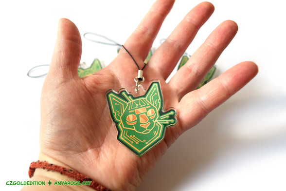 Hand holding an acrylic charm version of the cat made to resemble a printed circuit board (PCB), Circat.