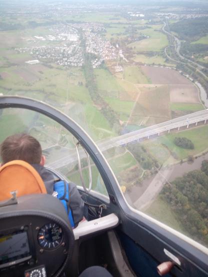 Blick aus dem Cockpit eines Segelflugzeugs während des Fluges. Das Segelflugzeug bewegt sich hierbei mit einem relativ steilen Winkel auf den Boden zu