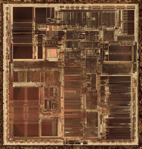 A detailed die photo of the Pentium chip. It has complex detailed patterns, with some large rectangular regions. The color is brownish and reddish.