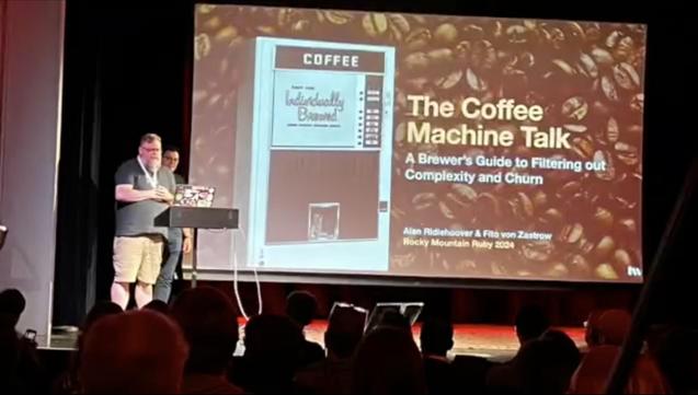 Alan Ridlehoover (with Fito von Zastrow) speaking to the Rocky Mountain Ruby audience in front of the title slide of a talk called The Coffee Machine Talk: A Brewer's Guide to Filtering out Complexity and Churn.