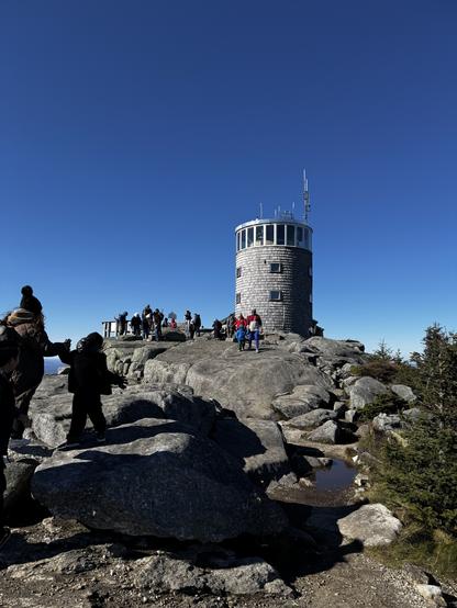 Picture of tower on the summit of Whiteface mountain. There is people walking the stony trail towards lookout points.
- - -
Photo de la tour au sommet du mont Whiteface. Il y a des personnes qui marchent le sentier rocheux vers les points d’observation.
