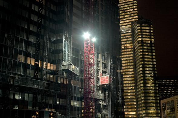 Échafaudage rouge devant un immeuble en contruction, une nuit de février 2013. La lumière au sommet de l'échaffaudage éclaire tous les détails du bâtiment non terminé.