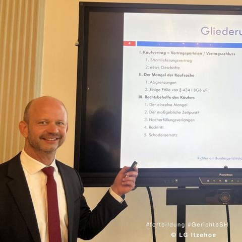 Richter am Bundesgerichtshof, Dr. Daniel Reichelt, vor Bildschirm mit Präsentation zum Thema Kaufrecht. Copyright LGItzehoe
