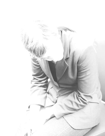The monochrome photo shows 
a person in a suit, sitting with his head bowed and appearing slightly blurred against a bright, overexposed background.