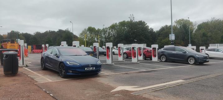 Rows of Tesla chargers adjacent to the Gridserve public charging. Ten Teslas can be seen charging.