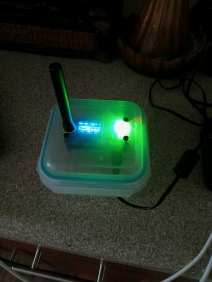 Photo of a DMR hotspot mounted inside a plastic food storage container.