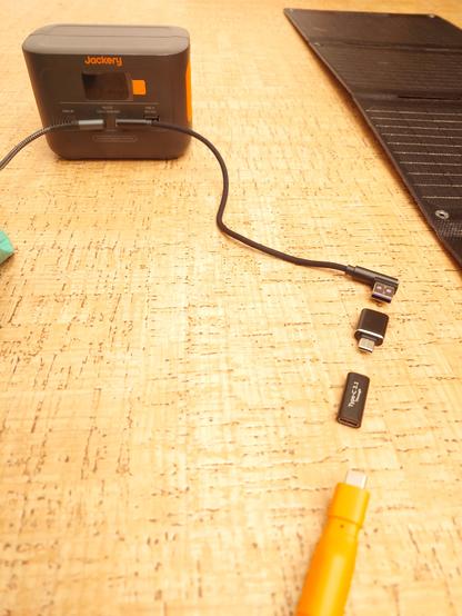 A series of USB adaptors (in exploded view) that make a male USB C from a solar panel into a female USB A socket for a USB C to USB A cable to charge the battery via the USB C port... in theory