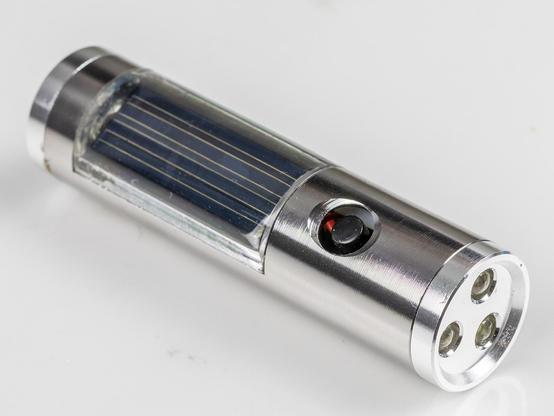 Kleine Taschenlampe mit Ausrichtung nach rechts unten. Links oben ist die Solarzelle im Gehäuse zu sehen, in der Mitte der Ein-/Ausschalter
