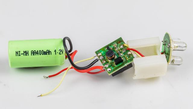 Gehäuse entfernt. Links ein grüner Ni-MH-Akku mit einer Kapazität von 400 mAh, in der Mitte der Ein-/Ausschalter mit kleiner Platine, rechts die 3 LEDs