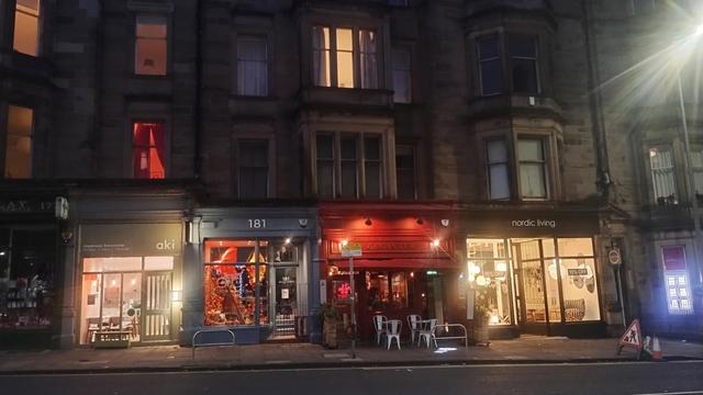 Looking across Bruntsfield Place at night, lights of restaurants and bistros on ground floor, Victorian stone tenements above
