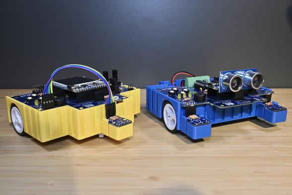 Two 3D-printed BEAPER Nano robots controlled by Arduino Nano ESP32 microcontrollers. The yellow robot has rear wheel drive and is configured as a line follower while the blue robot has front wheel drive with floor sensors and a SONAR module to sense its environment.