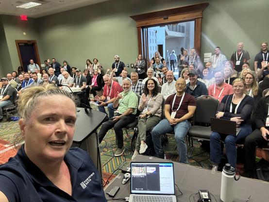Selfie of a woman in front of a classroom full of adult students