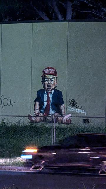 A caricature of Donald Trump as an angry baby in a diaper. Spray paint on concrete. Artist unknown.