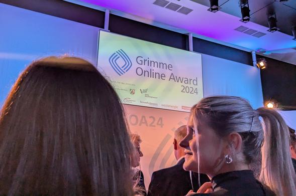 Foto von der Leinwand Grimme Online Award, im Publikum eine junge Frau, ihr Gesicht im Profil