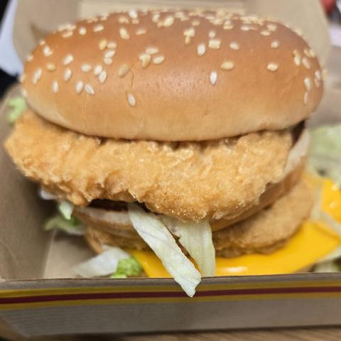 Photograph of a chicken sandwich in a box. It has two patties, a sesame seed bun, and lettuce / cheese are both visible. There's some kind of special sauce on it. It's a chicken Big Mac.