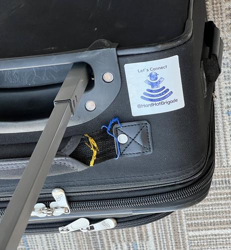 A picture of a suitcase with a HardHatBrigade sticker saying “Let’s connect”