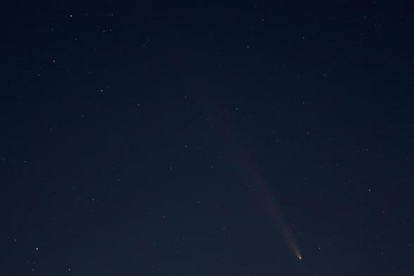 Comet A3 in a dark, starry frame, pointing down with a long trail stretching above it at the 10 o’clock position.