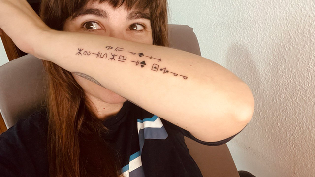 Tatuaje en el antebrazo, el lado externo. Es el críptico escrito en el idioma de Bill Cipher con el que engañó a Ford diciéndole que decía "hombre sabio" y en realidad pone "si se pierde, devolver a Bill". Realmente es en inglés y pone "if lost return to Bill".
