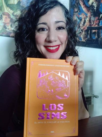 Laura posa sonriente con su libro de Los Sims: El arte de simular la vida real.