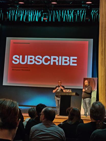Tim Pritlove auf der Bühne, auf der Leinwand der Schriftzug "Subscribe. Ein kurzer Rückblick"