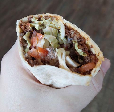 This is a photo of a kebab that was made by me and my girlfriend. Her lovely hand that is grasping tortilla filled with yogurt vegetable mix and juicy tasty soy granulate seasoned with soy sauce kebab and gyros spice mix and dash of smoked paprika.