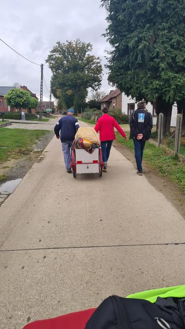A man and a woman pull the cart over the road, another man walking beside them