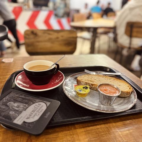 Pack de desayuno con bandeja con café extremadamente rico con leche fría de avena y tostada de pan blanco con aceite y tomate. Y el Kobo con Carmilla.