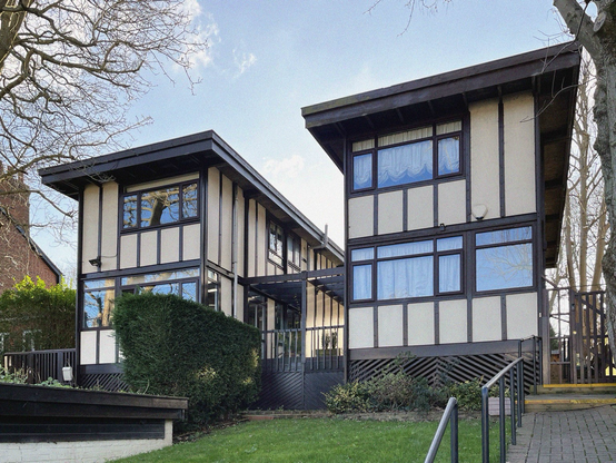 A colour photograph of two semi detached self built timber houses in Sydenham