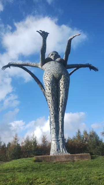 Standing in front of the statue, looking straight up , autumn sunlight on one side of it, blue skies above