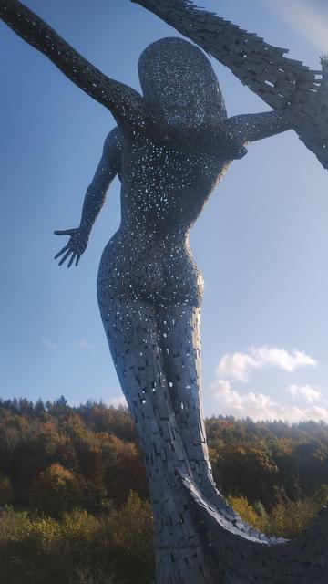 Rear view of the statue from the shaded side, seen against the blue sky and colours of the autumn trees