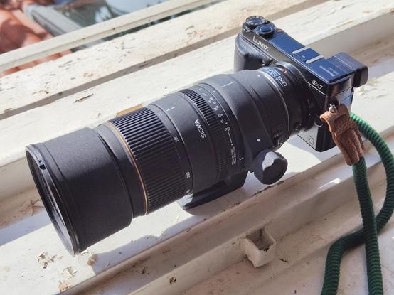 Sigma 135-400mm F4.5-5.6 APO DG lens mounted on a Panasonic GX7 camera sitting on a window sill.