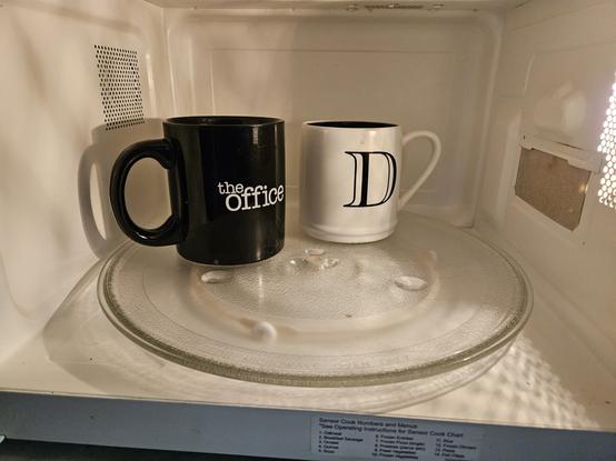 Two coffee cups in a microwave.